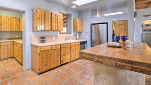 A kitchen with wooden cabinets, a central island, a stainless steel refrigerator, and a large window. - Las Cruces Adobe Near Mesilla & Nmsu (Las Cruces)