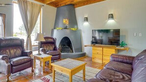 A living room with leather sofas, a fireplace, a television, and wooden ceiling beams. - Las Cruces Adobe Near Mesilla & Nmsu (Las Cruces)