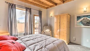 A bedroom with a wooden ceiling, a bed with a grey quilt, a wooden wardrobe, a chair, and a painting on the wall. - Las Cruces Adobe Near Mesilla & Nmsu (Las Cruces)