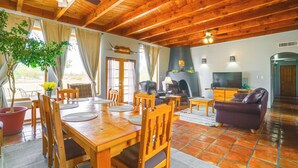 A wooden dining area with a table and chairs, a sofa, and a television. - Las Cruces Adobe Near Mesilla & Nmsu (Las Cruces)