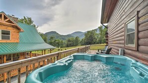 Ein Whirlpool auf einer Holzterrasse mit Blick auf Berge und ein Gebäude mit Gründach.