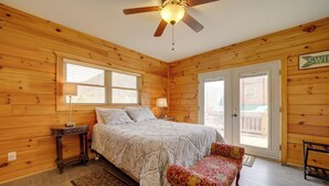Ein Schlafzimmer einer Holzhütte mit Bett, Nachttischen, einer Bank und einem Deckenventilator.