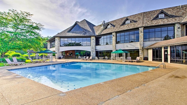 A hotel with a swimming pool, outdoor seating, and a covered patio area.