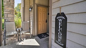A house entrance with a welcome sign, a door, and two chairs outside.