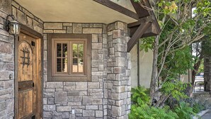 Eine Fassade aus Stein mit einer Holztür und einem Fenster, einer Fußmatte und einem kleinen Garten.