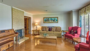 A living room with a piano, a sofa, a red armchair, and a painting on the wall. - Spacious Downtown Montgomery Home w/ Yard, Patio! (Montgomery)