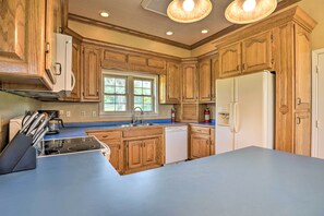 A kitchen with wooden cabinets, a white refrigerator, a dishwasher, and a blue countertop.