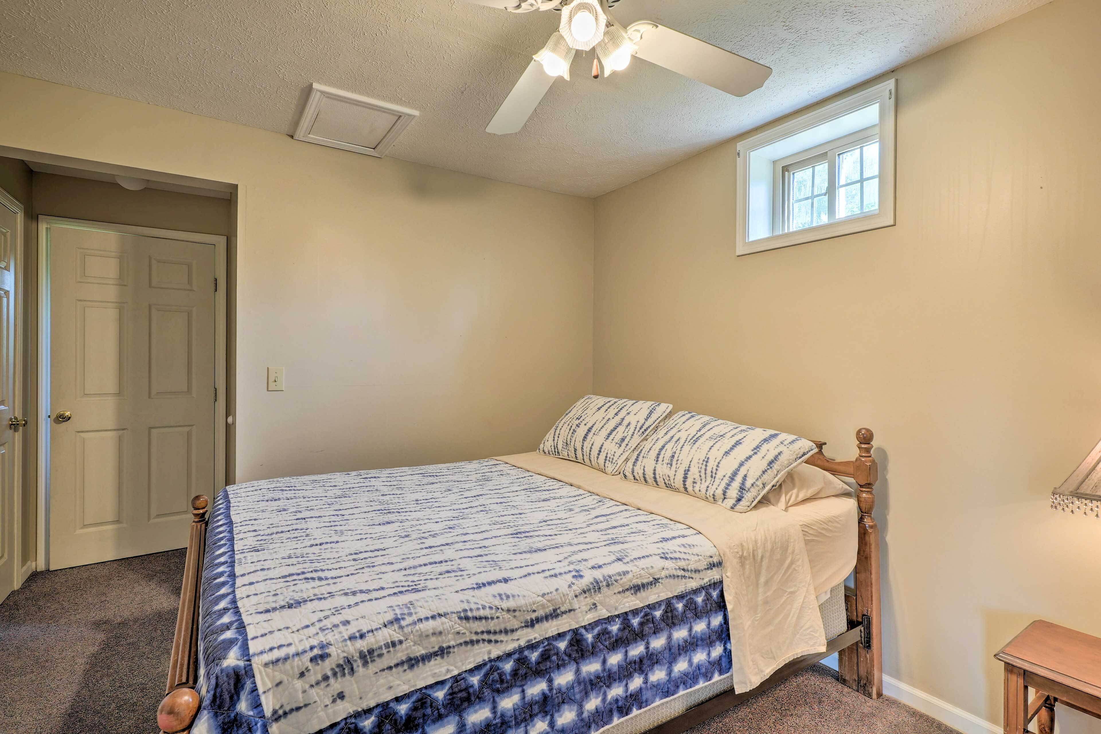 A bedroom with a bed, a ceiling fan, a window, and a door.