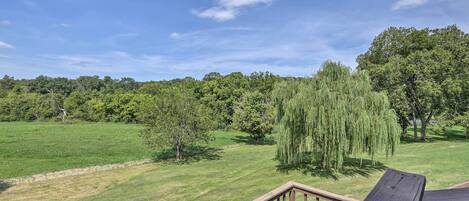A wooden deck with a view of a grassy field and trees.
