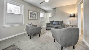 A living room with grey sofas, a ceiling fan, and a carpeted floor.