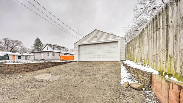 A garage with a white door, a brick wall, and a wooden fence with snow on it.