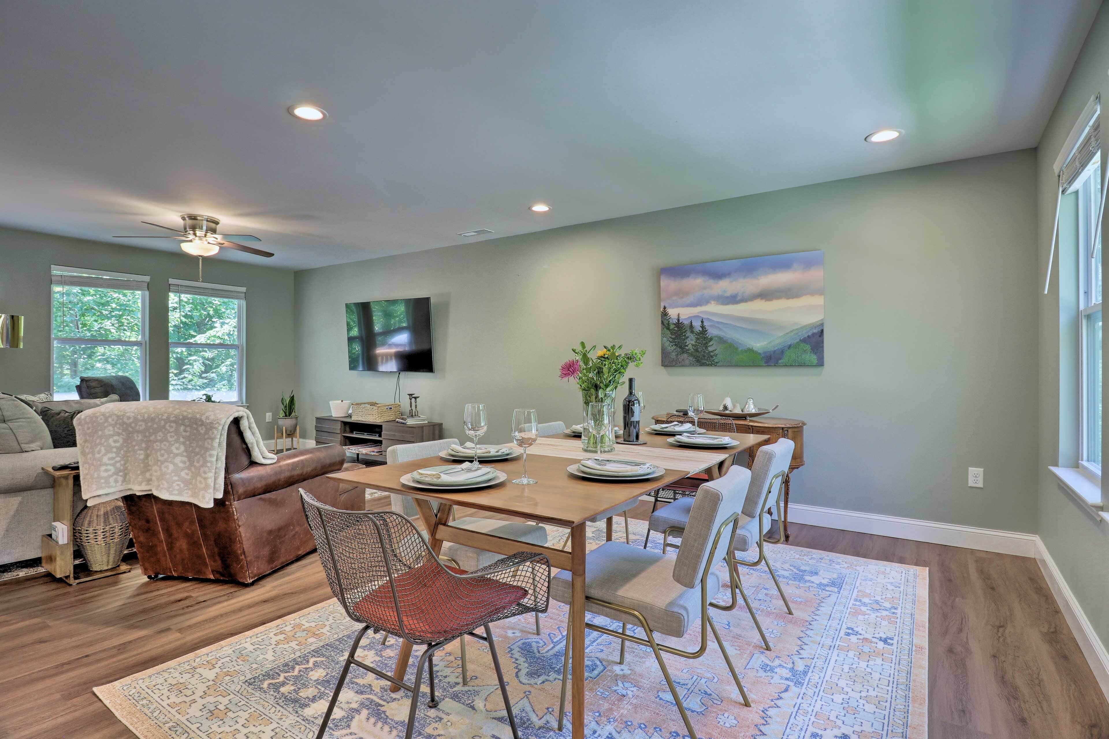 A dining area with a table set for four, a sofa, and a TV in the background.