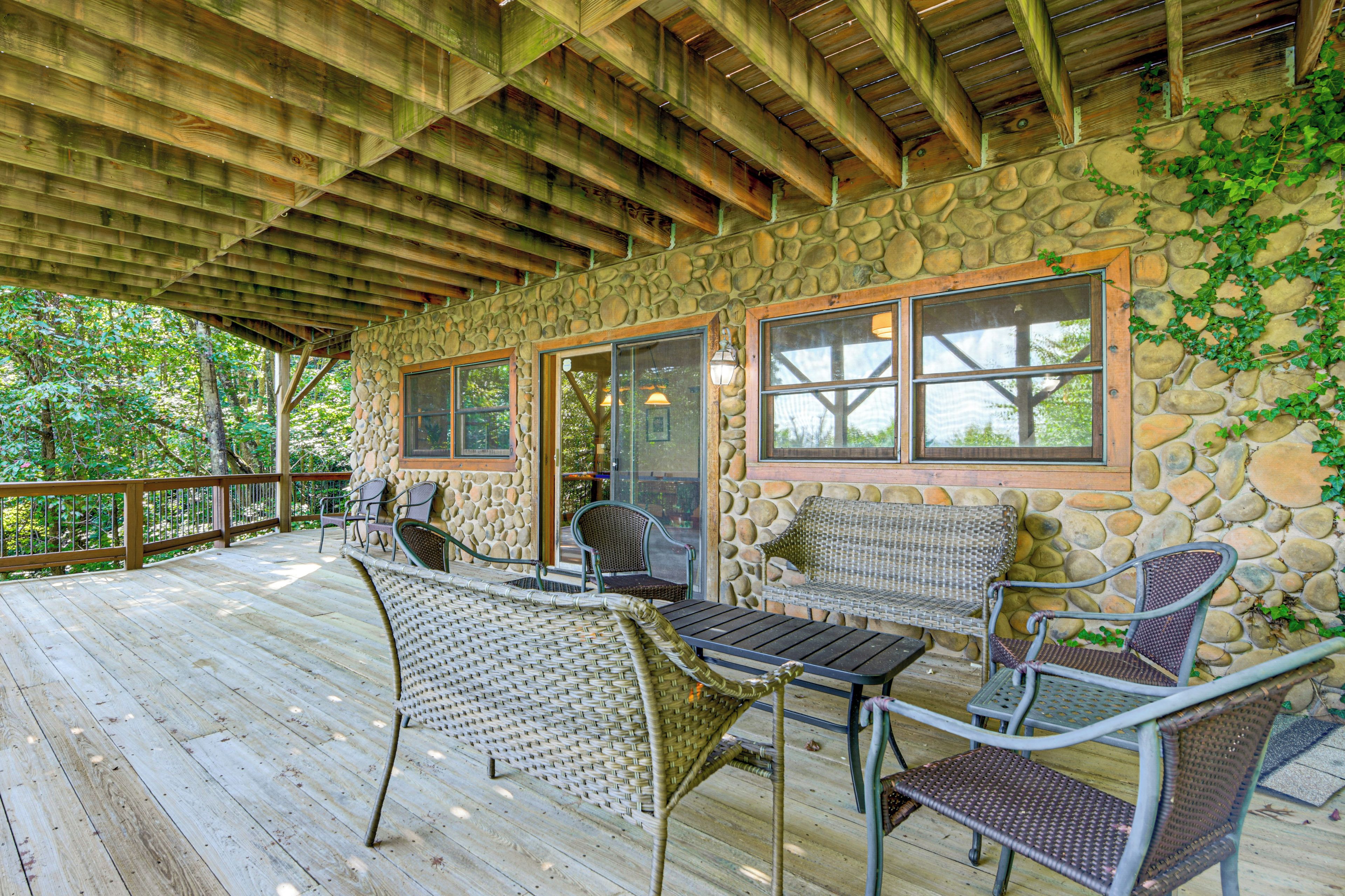 A covered outdoor area with stone walls, wooden beams, and wicker furniture.