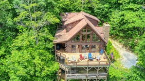 Eine Holzhütte mit einer Terrasse, umgeben von dichtem Wald.
