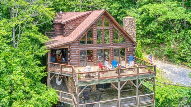 Eine Blockhütte mit Balkon, umgeben von üppigem Grün.