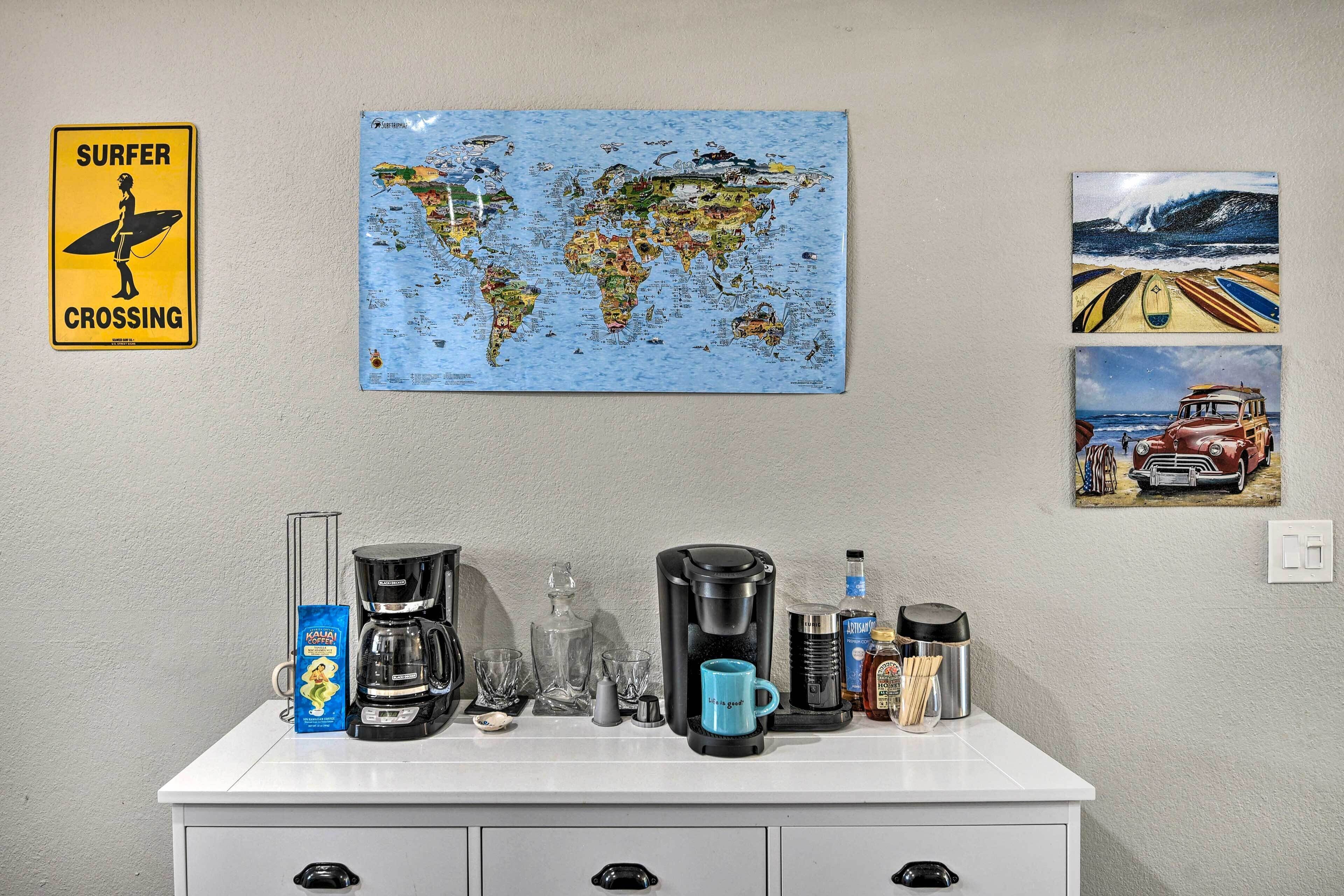 Una encimera de cocina con una cafetera, un mapa del mundo y dos fotografías enmarcadas.
