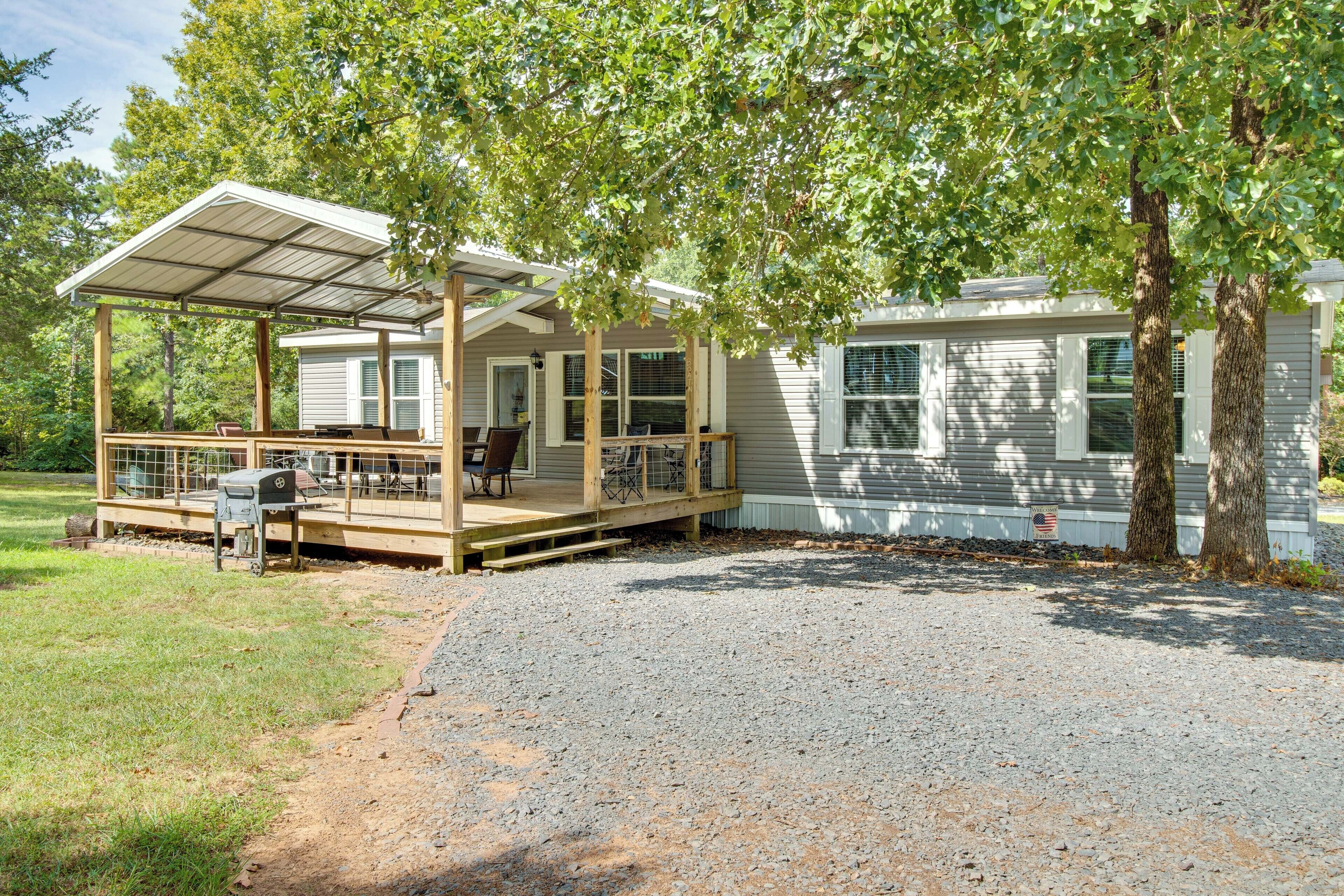 A mobile home with a covered porch, outdoor seating, and a grill.