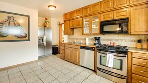 A modern kitchen with wooden cabinets, stainless steel appliances, and a tiled floor. - Spacious Wyoming Retreat: Fishing & Hunting (Torrington)