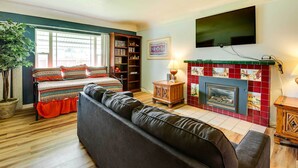 A living room with a sofa, a fireplace, a television, and a bookshelf. - Spacious Wyoming Retreat: Fishing & Hunting (Torrington)