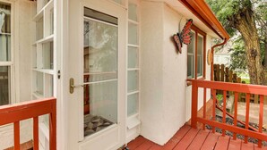 A wooden deck with a red railing, a glass door with a butterfly decoration, and a welcome mat. - Spacious Wyoming Retreat: Fishing & Hunting (Torrington)