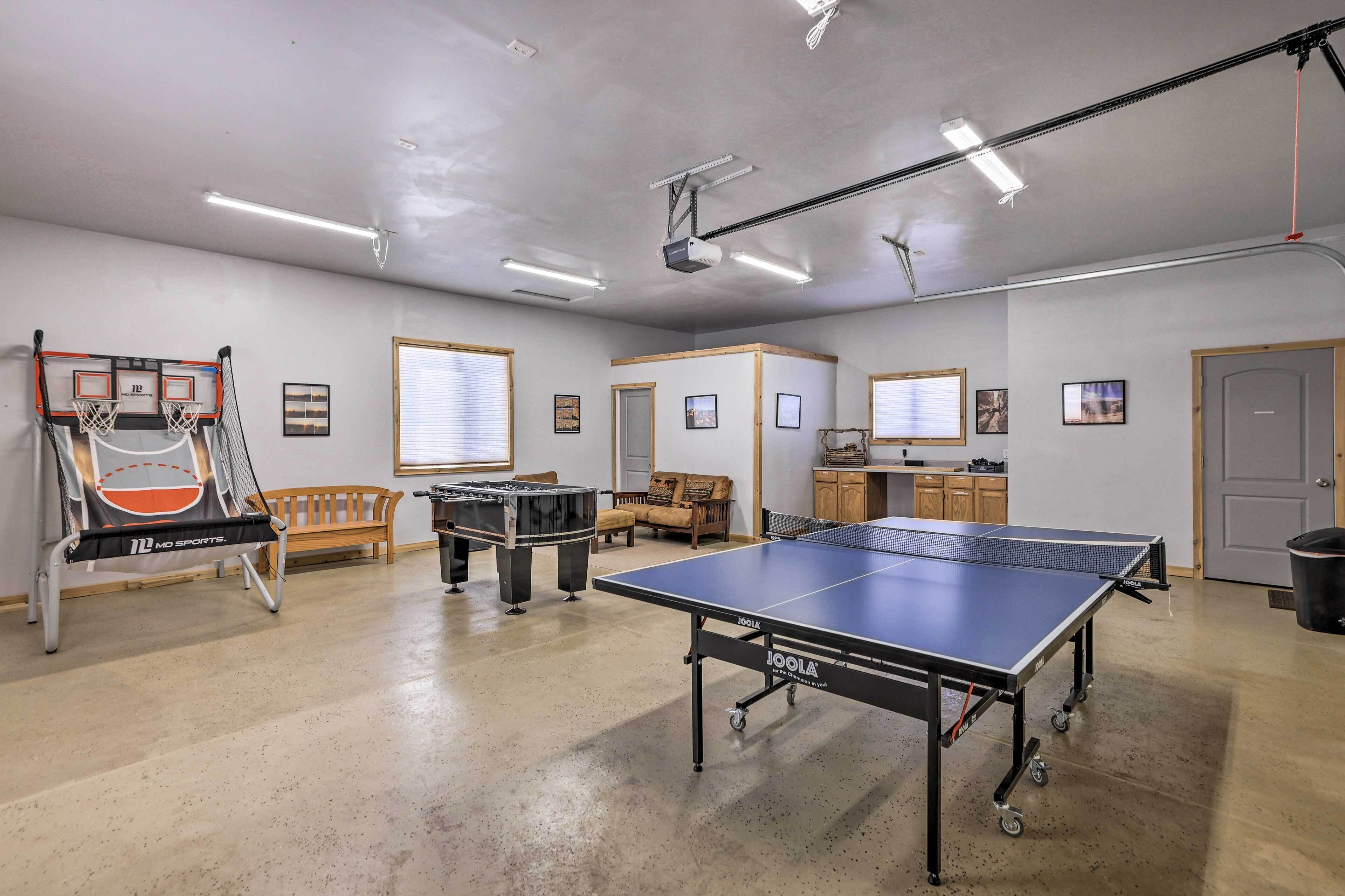 A spacious indoor area with a ping pong table, a foosball table, and a basketball hoop.
