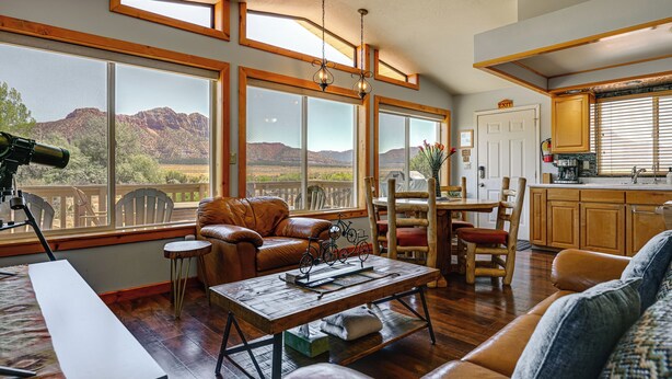 Un salon spacieux avec de grandes fenêtres, un canapé en cuir, une table basse en bois et une vue sur les montagnes.