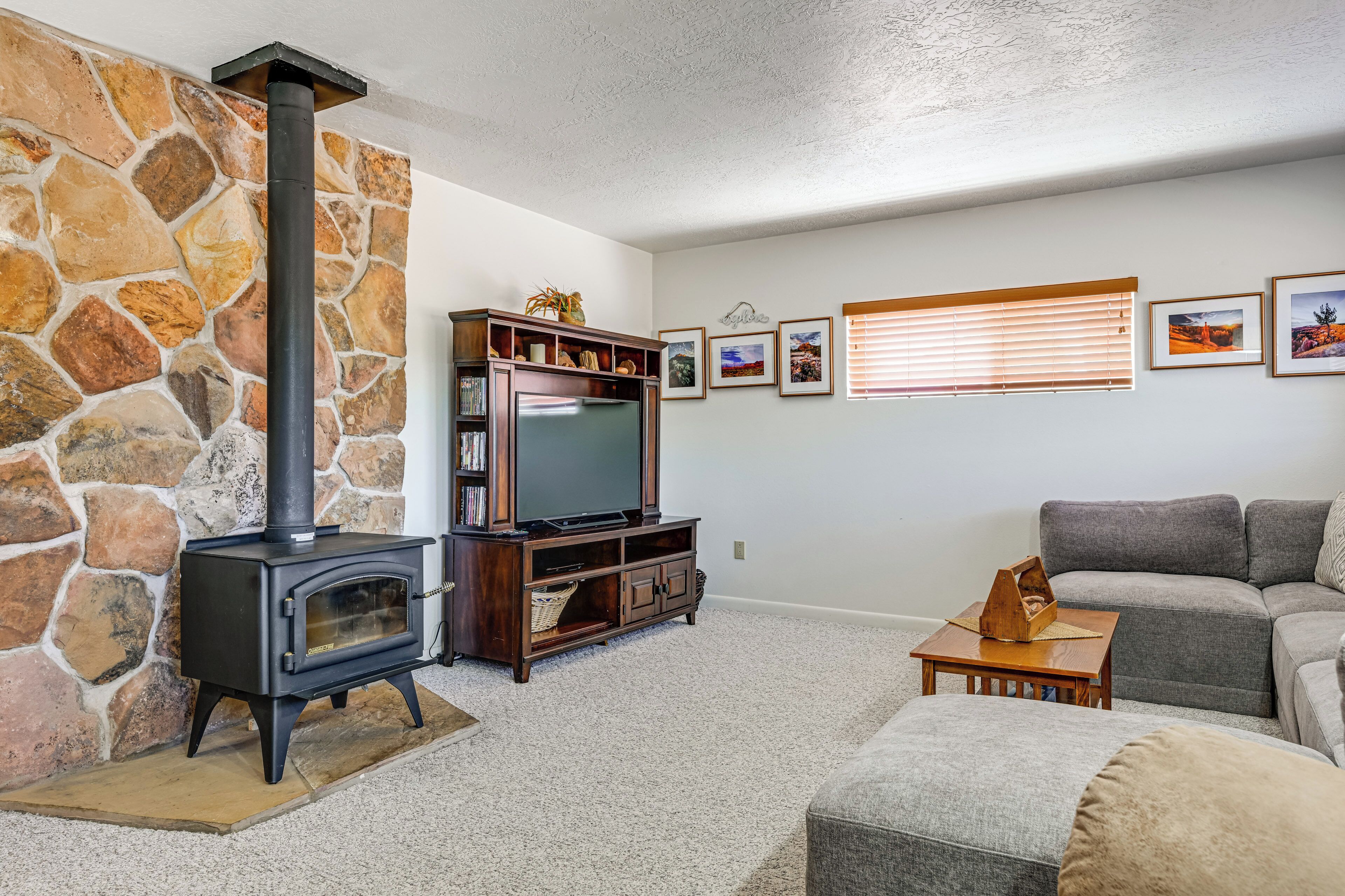 A living room with a stone wall, a fireplace, a television, and a sofa.