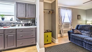 A modern kitchen with grey cabinets, a green chest of drawers, and a marble backsplash.