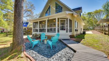 A two-story house with a covered porch, outdoor seating area, and a wooden deck.