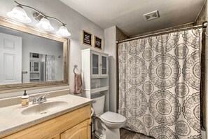 A bathroom with a sink, mirror, cabinet, toilet, and shower curtain.