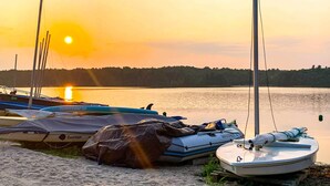 A lakeside scene with boats and a sailboat docked near the shore. - Walk to Beach: Beautiful Lake Naomi Retreat! (Pocono Pines)