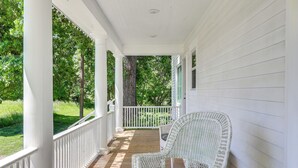 A covered porch with a wicker chair and a white railing. - Home Near Downtown & Spearfish Canyon! (Spearfish)