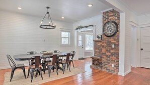 A dining area with a brick fireplace, white paneled walls, and a chandelier. - Home Near Downtown & Spearfish Canyon! (Spearfish)