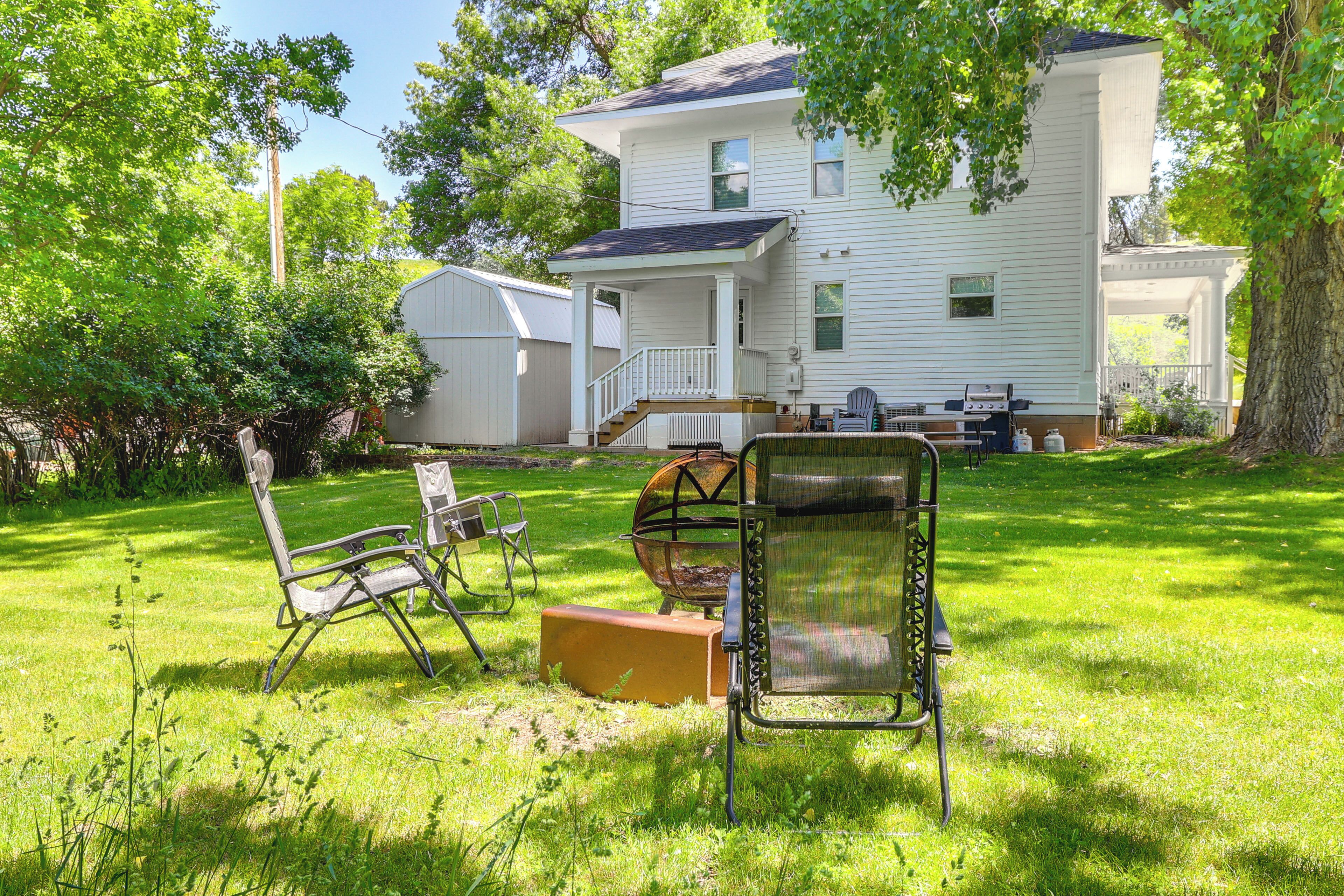 A two-story house with a porch, a grill, and outdoor furniture.