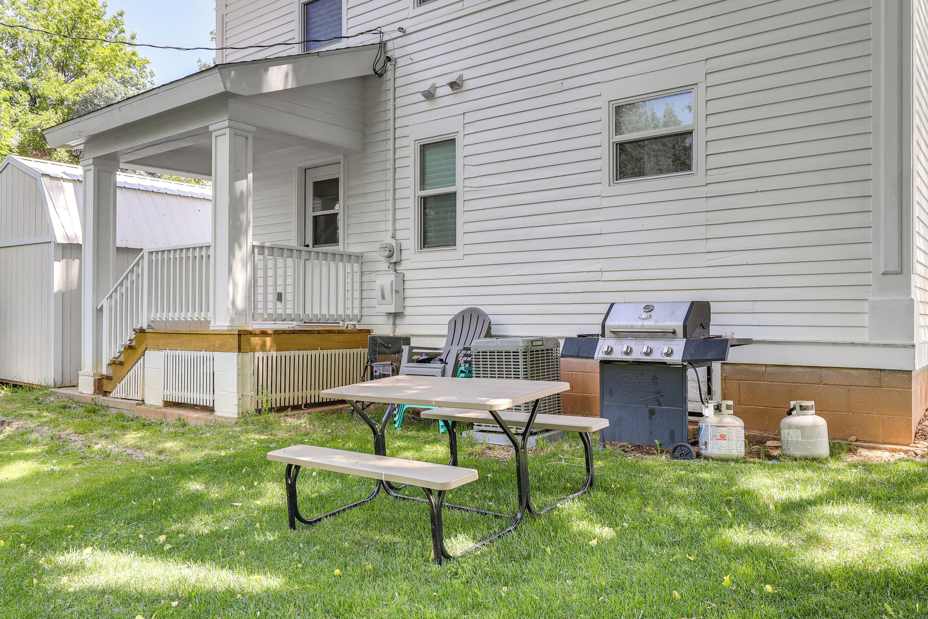 A backyard with a picnic table, grill, and outdoor seating.