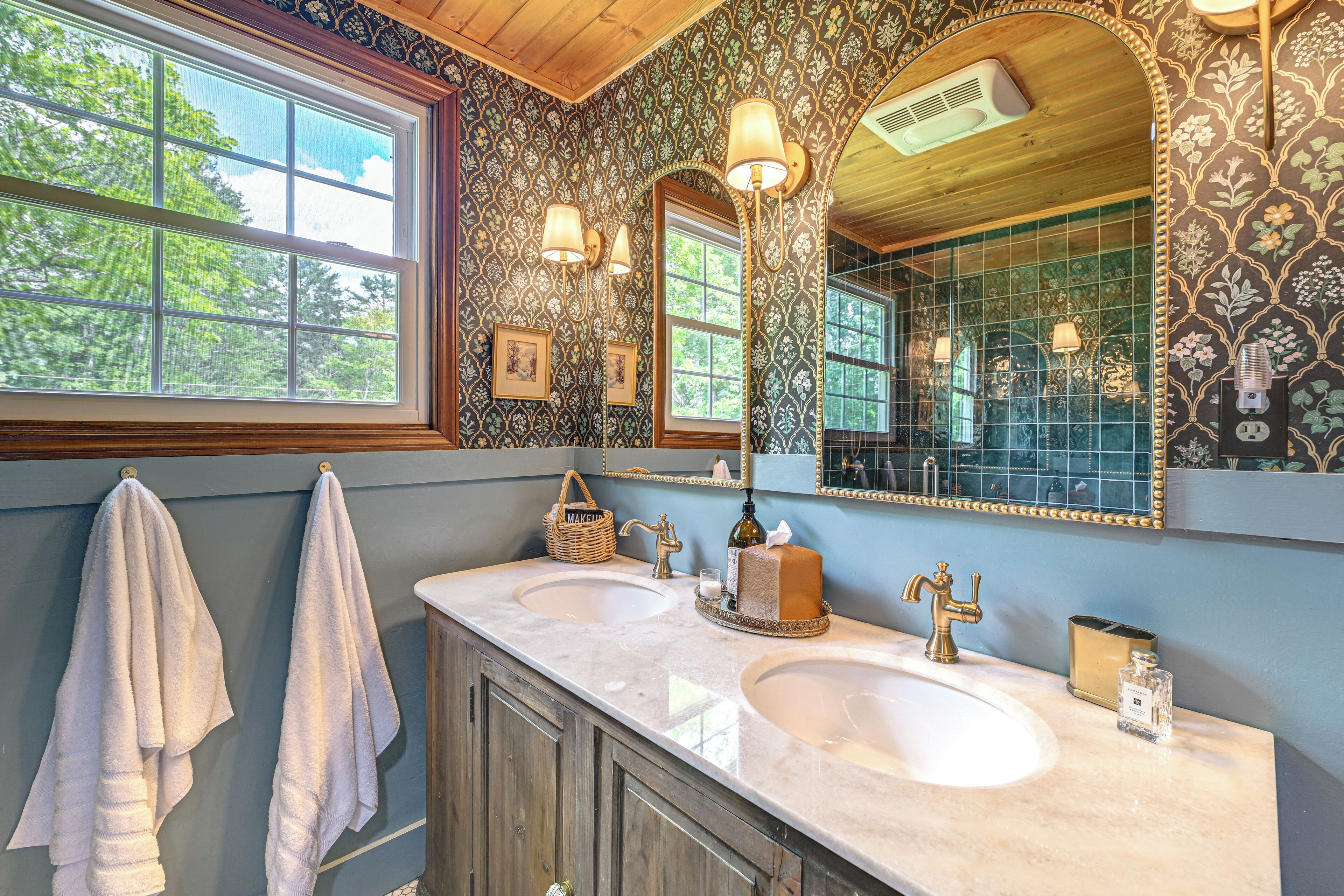A bathroom with two sinks, a large mirror, and patterned wallpaper.