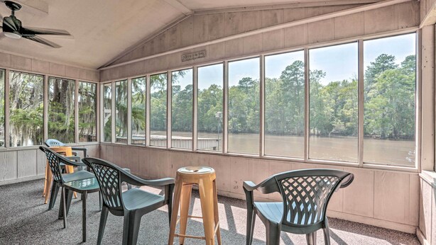A room with large windows overlooking a river, wooden walls, and plastic chairs. - Sues Camp w/ Caddo Lake Access & Dock! (Karnack)