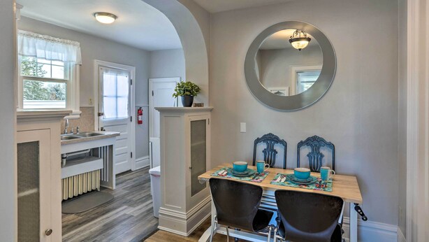 A dining area with a table set for two, a large mirror on the wall, and a kitchen in the background. - 2nd-floor Dillon Apt - Near University & Fishing! (Dillon)