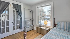 A bedroom with a bed, a radiator, a window with a view of trees, a door with curtains, and a storage unit with a hanging rack. - 2nd-floor Dillon Apt - Near University & Fishing! (Dillon)