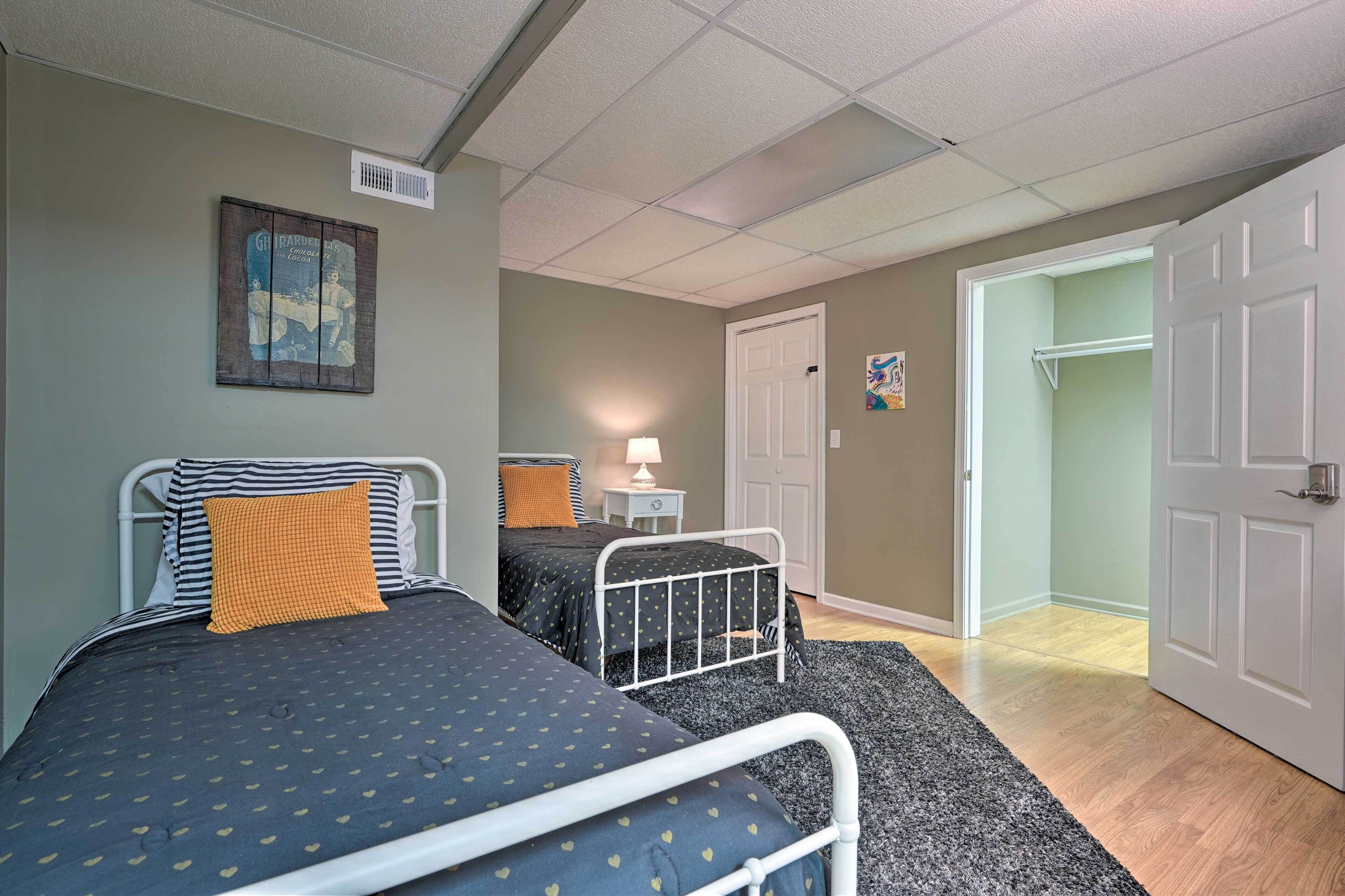 Een slaapkamer met twee bedden, een nachtkastje, een lamp en een deur naar een andere kamer.