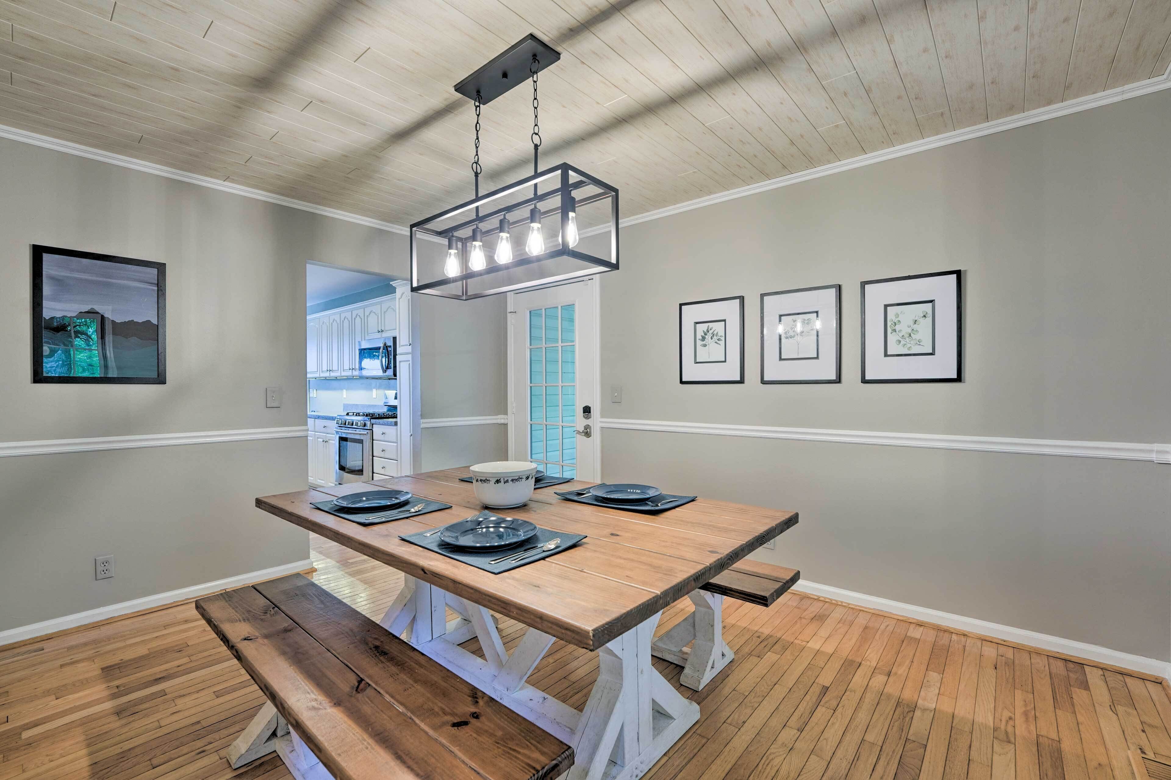 A dining area with a wooden table, benches, and a hanging light fixture.