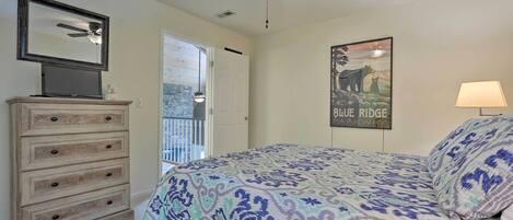 A bedroom with a bed, dresser, ceiling fan, and a poster on the wall.