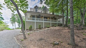 A two-story house with a porch, surrounded by trees.
