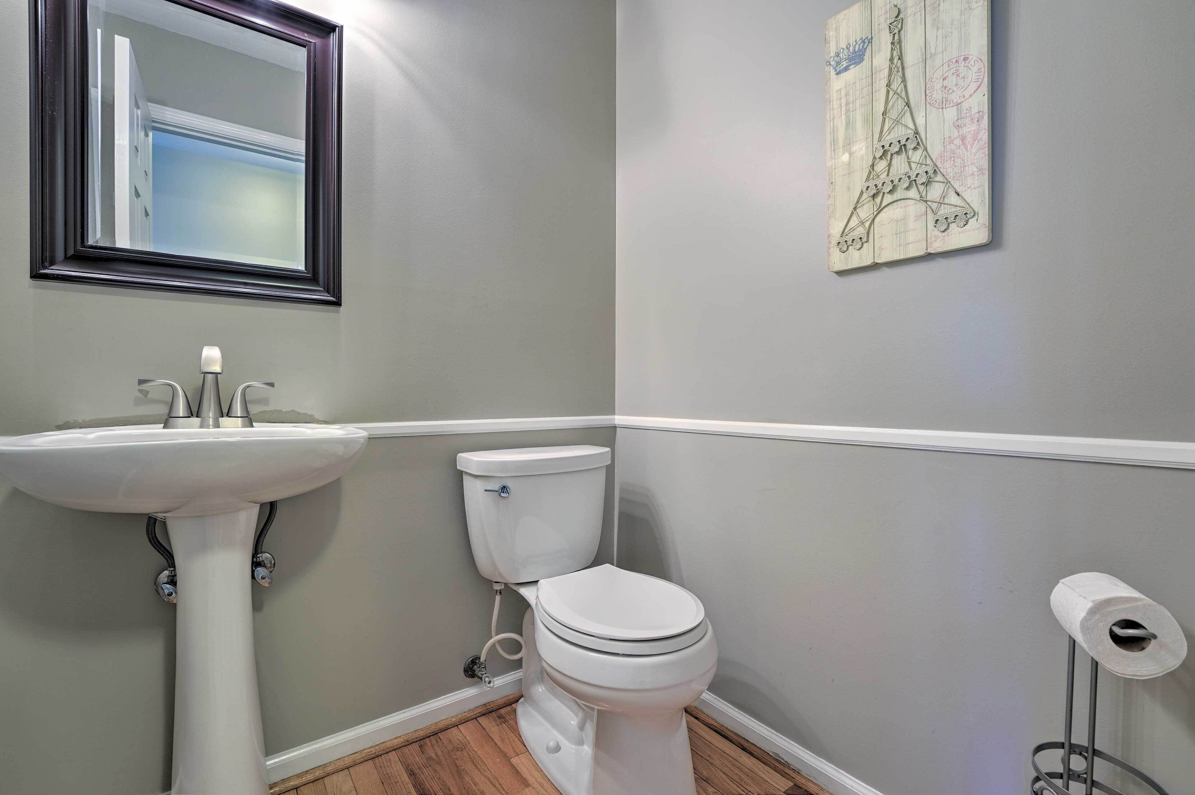 A bathroom with a pedestal sink, toilet, and a framed picture of the Eiffel Tower.