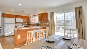 A modern kitchen with wooden cabinets, a central island, and a dining area with a table and chairs. - Serene Pocono Escape: 4 Mi to Tobyhanna State Park (Tobyhanna)