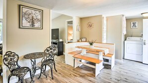 A dining area with a round table and chairs, a bench, a wall clock, and a laundry room with a washing machine. - Cozy House w/ Huge Yard ~ 16 Mi to Fort Bragg (Lillington)