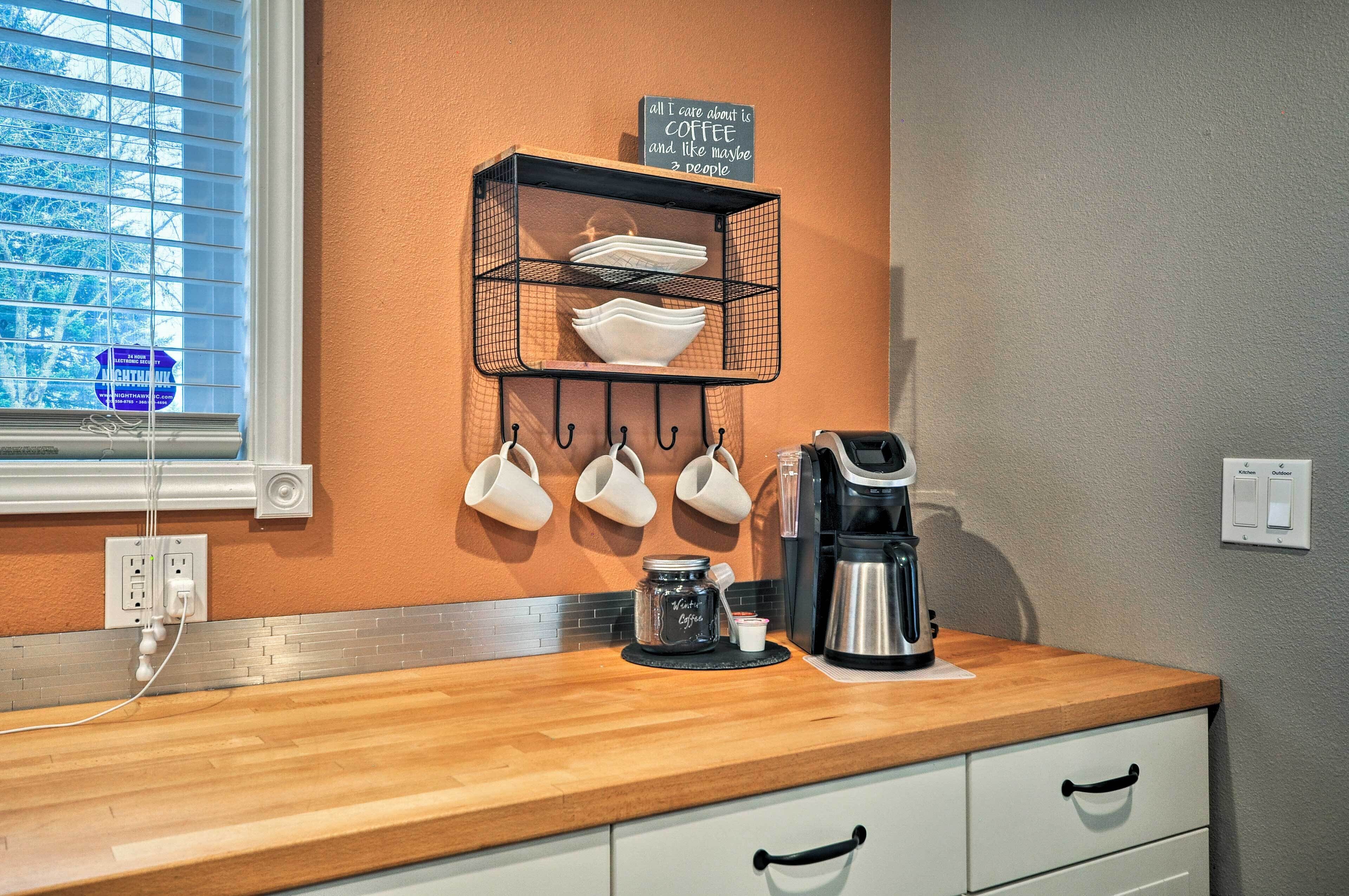 A kitchen with a coffee station, including a coffee maker, cups, and a sign that says "all I care about is coffee and maybe 3 people."