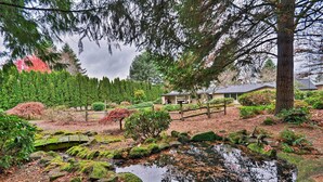 A serene garden with a pond, wooden fence, and neatly trimmed bushes. - Cute & Cozy PDX Area Townhouse: 31 Mi to Mt. Hood! (Boring)