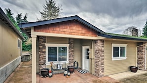 A house with a covered porch, stone pillars, and a small garden area with a bench and potted plants. - Cute & Cozy PDX Area Townhouse: 31 Mi to Mt. Hood! (Boring)
