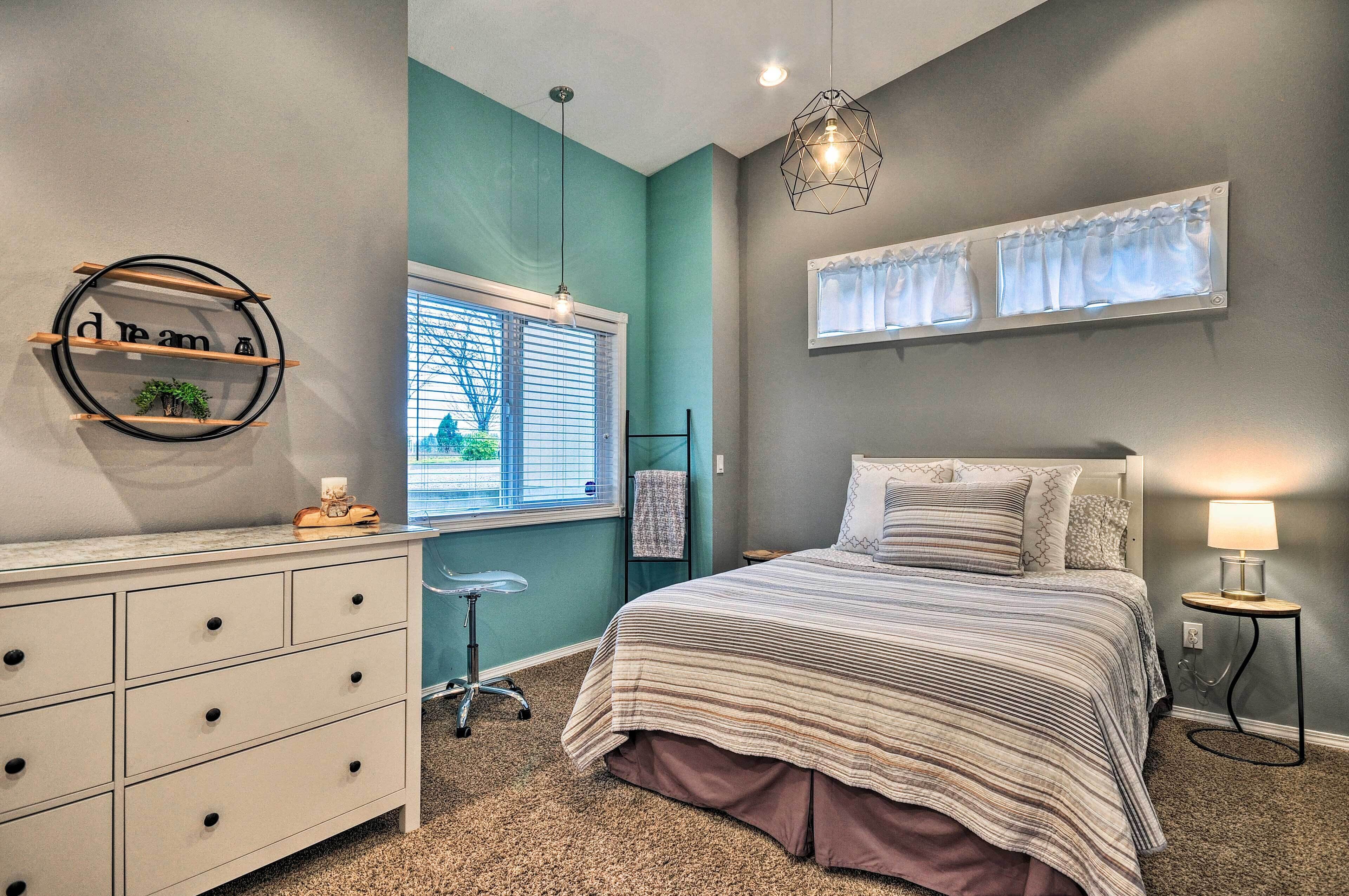 A bedroom with a bed, dresser, and window with blinds.